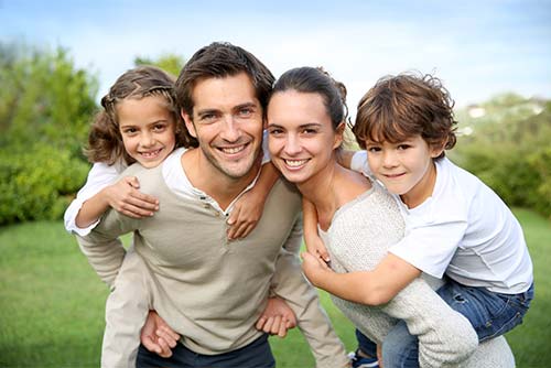 family of smiling people standing in a grassy field